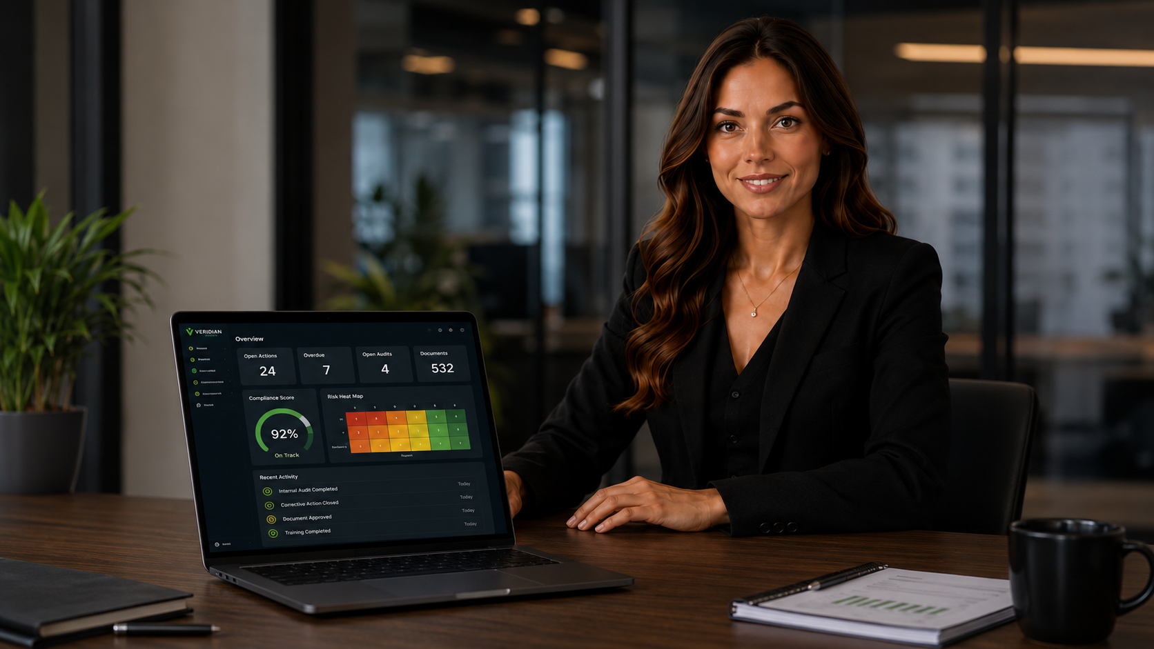 Compliance manager reviewing the Veridian IMS operational dashboard on a laptop, showing open actions, compliance score and risk heat map